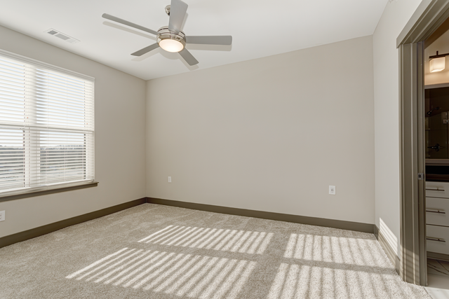an empty room with a ceiling fan and a window