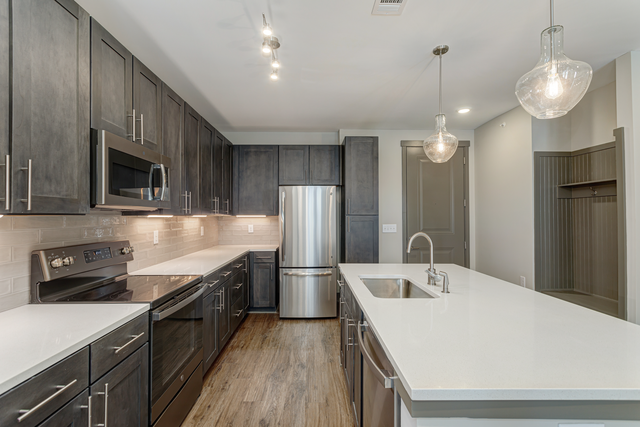 a kitchen with white counter tops and dark wood cabinets