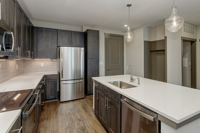 a kitchen with white counter tops and a stainless steel refrigerator