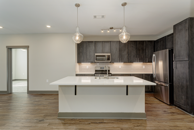 a kitchen with a large white island and dark cabinets