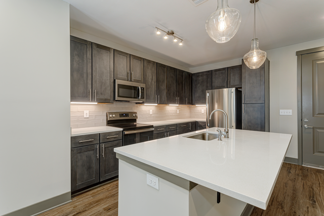 a kitchen with a large white counter top and dark cabinets