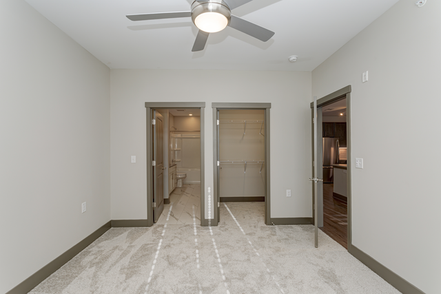 a renovated living room with a ceiling fan and two closets