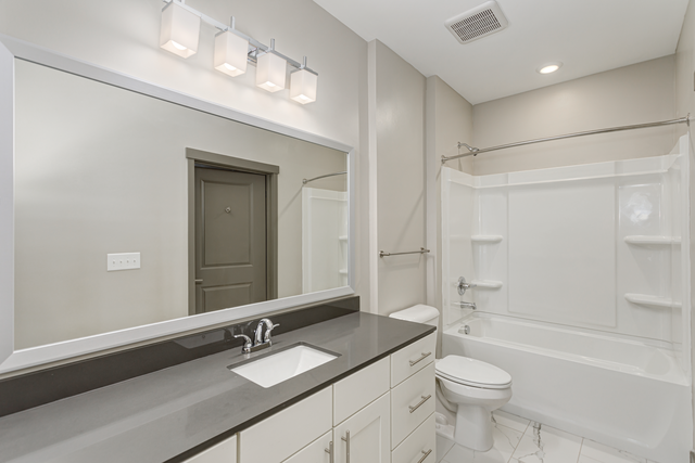 a white bathroom with a large mirror and a white toilet and sink