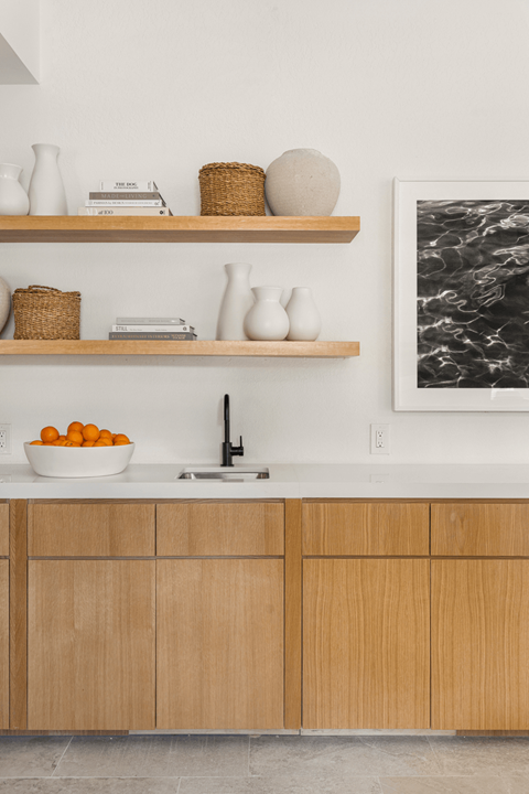 A kitchen with wooden cabinets and shelves with various items on them.