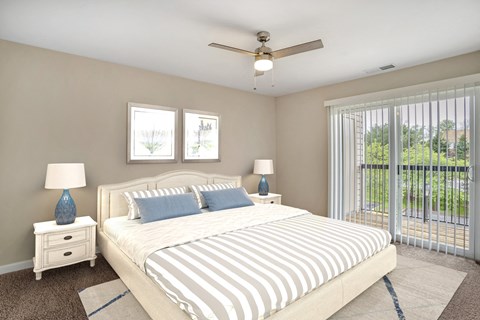 A virtually staged bedroom with gray walls with white trim, dark gray carpet throughout, and sliding glass door with vertical blinds leading to the outside patio/balcony area.
