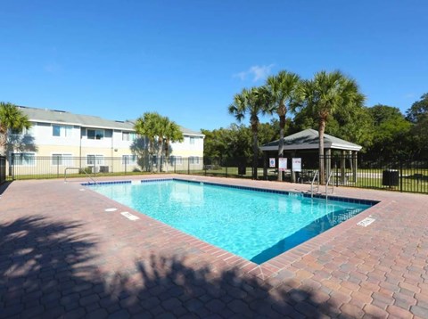 A swimming pool surrounded by a brick patio and a gazebo.
