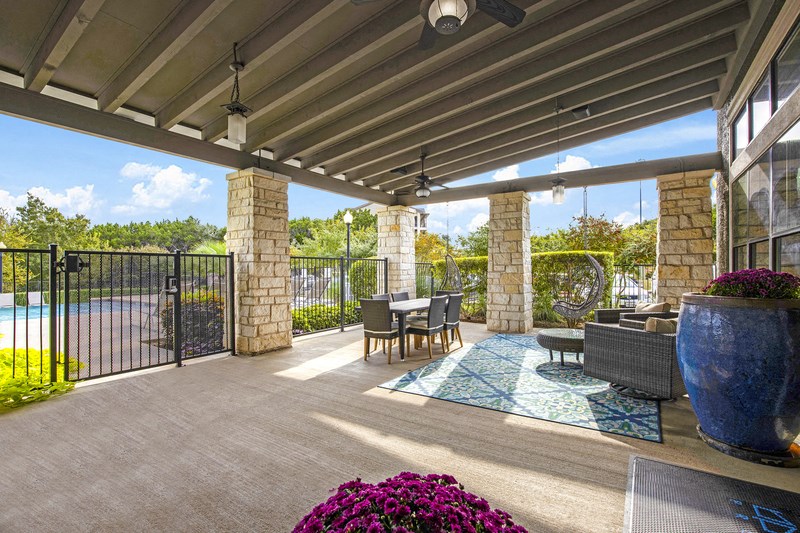 a covered patio with a table and chairs and a swimming pool