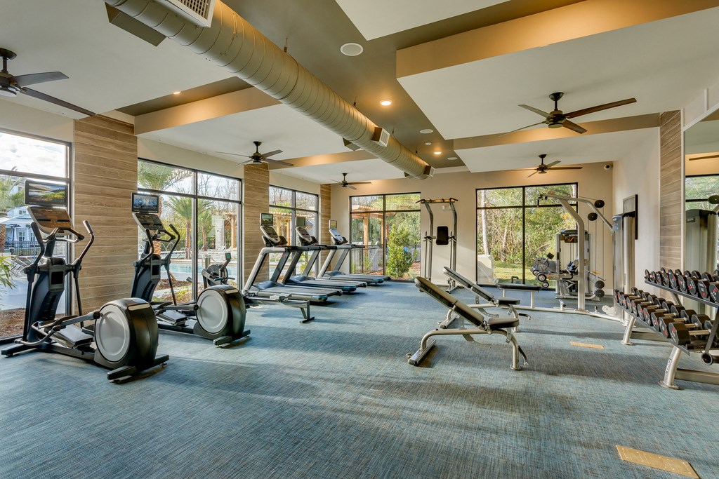 a gym with cardio equipment and windows on the side of a building