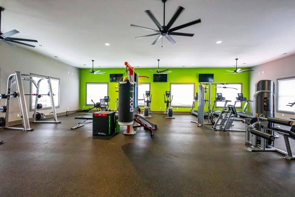A gym with a green wall and a black ceiling fan. at Foxwood Apartments, North Carolina