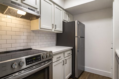 A kitchen with a stove top oven and a refrigerator.