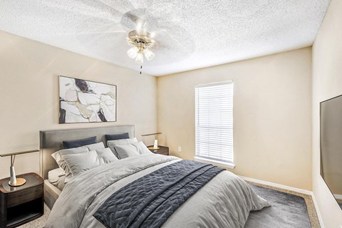 Bedroom with queen size bed, night stand with lamp and a ceiling fan