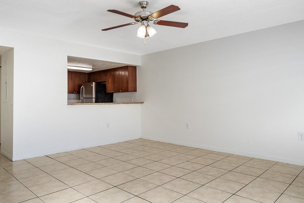 Tiled Living Room with Breakfast Bar Connected to Kitchen with Wood Cabinets, Tan Counters and Stainless Steel Appliances