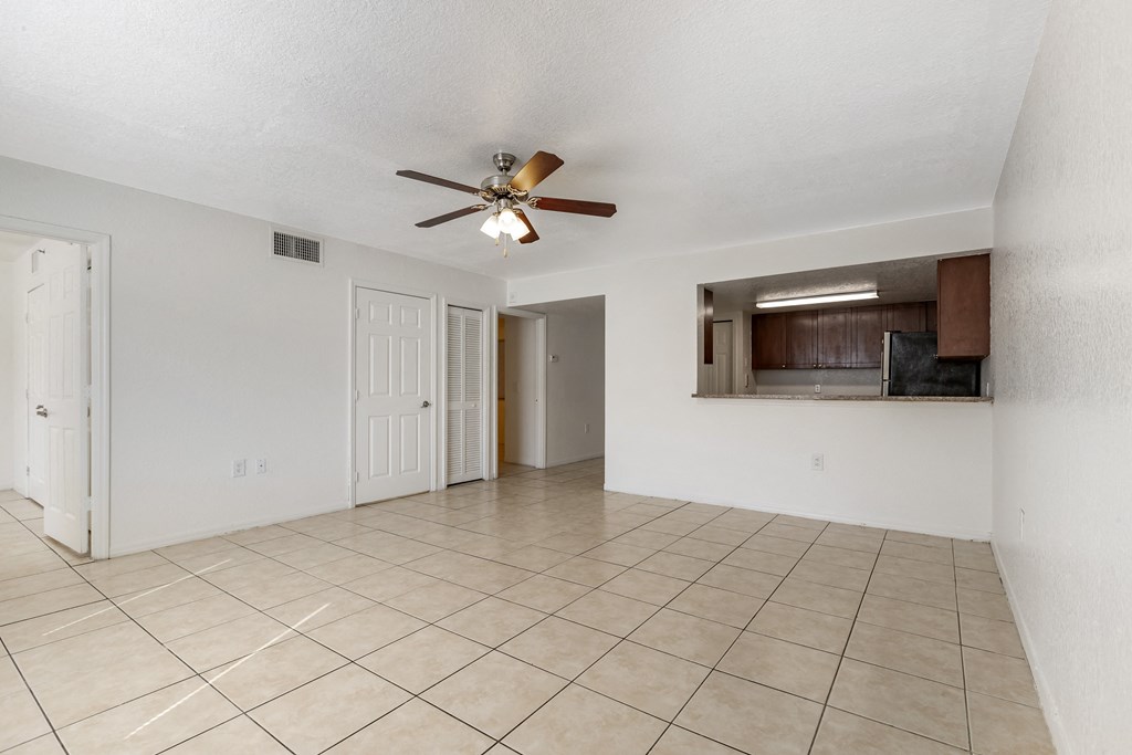 Tiled Living Room with Breakfast Bar Connected to Kitchen with Wood Cabinets, Tan Counters and Stainless Steel Appliances