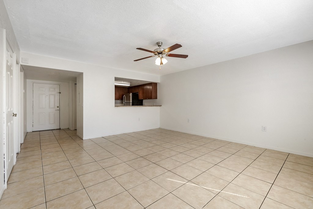 Tiled Living Room with Breakfast Bar Connected to Kitchen with Wood Cabinets, Tan Counters and Stainless Steel Appliances