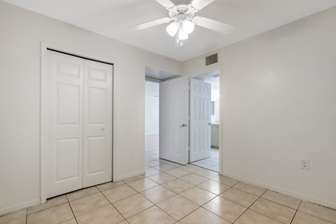 the living room and entryway of a house with white doors and a ceiling fan