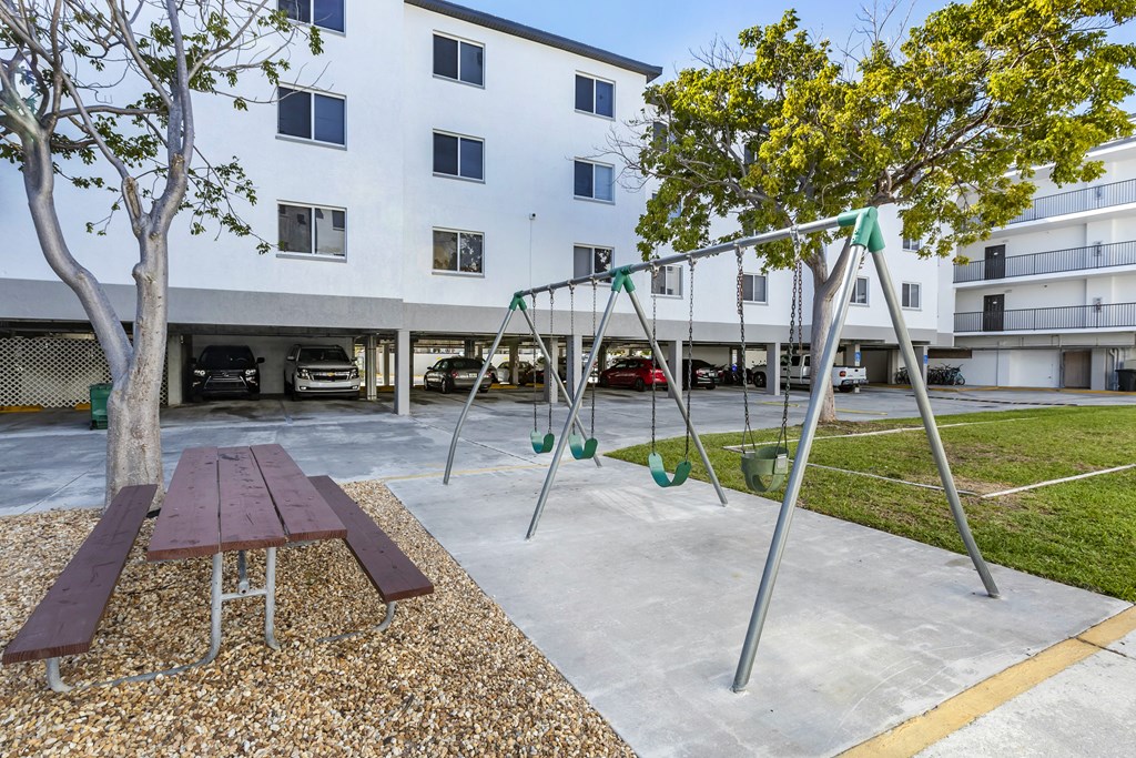 Swing Set in Front Of Picnic Tables Between Building Exteriors