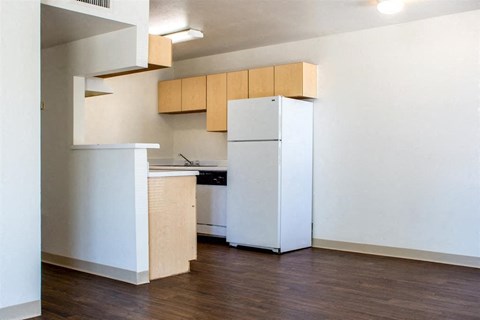 A kitchen with a white fridge and wooden cabinets.