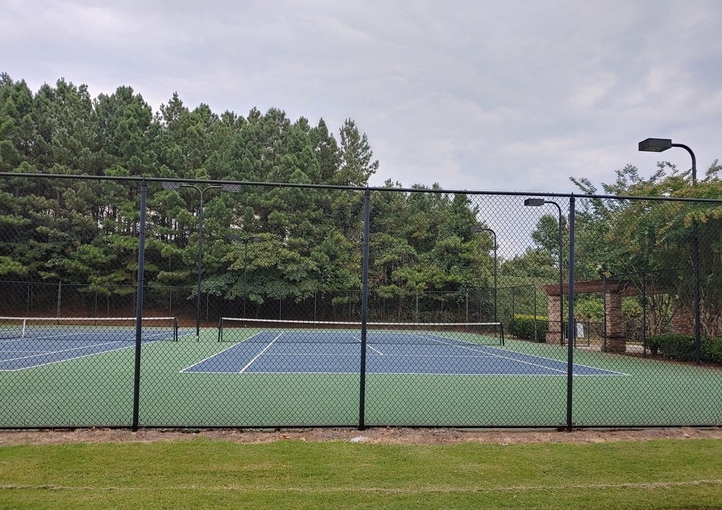 a tennis court with a fence around it and trees
