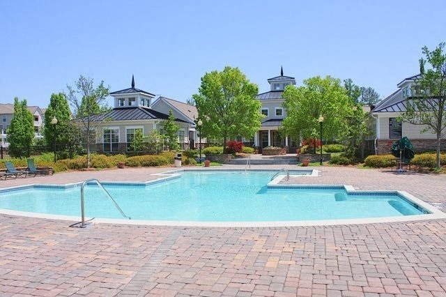 a swimming pool and a spa with a house in the background
