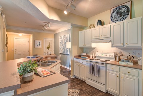 a kitchen with white cabinets and white appliances and a sink