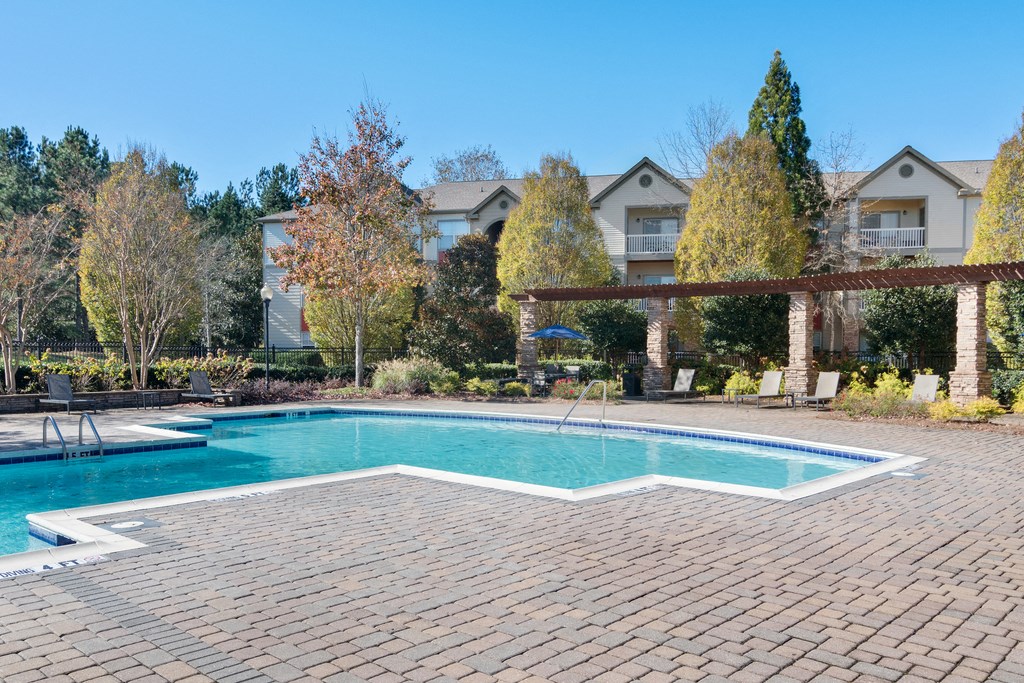 Poolside shade, lounge seating, swimming pool, and apartment building in the background