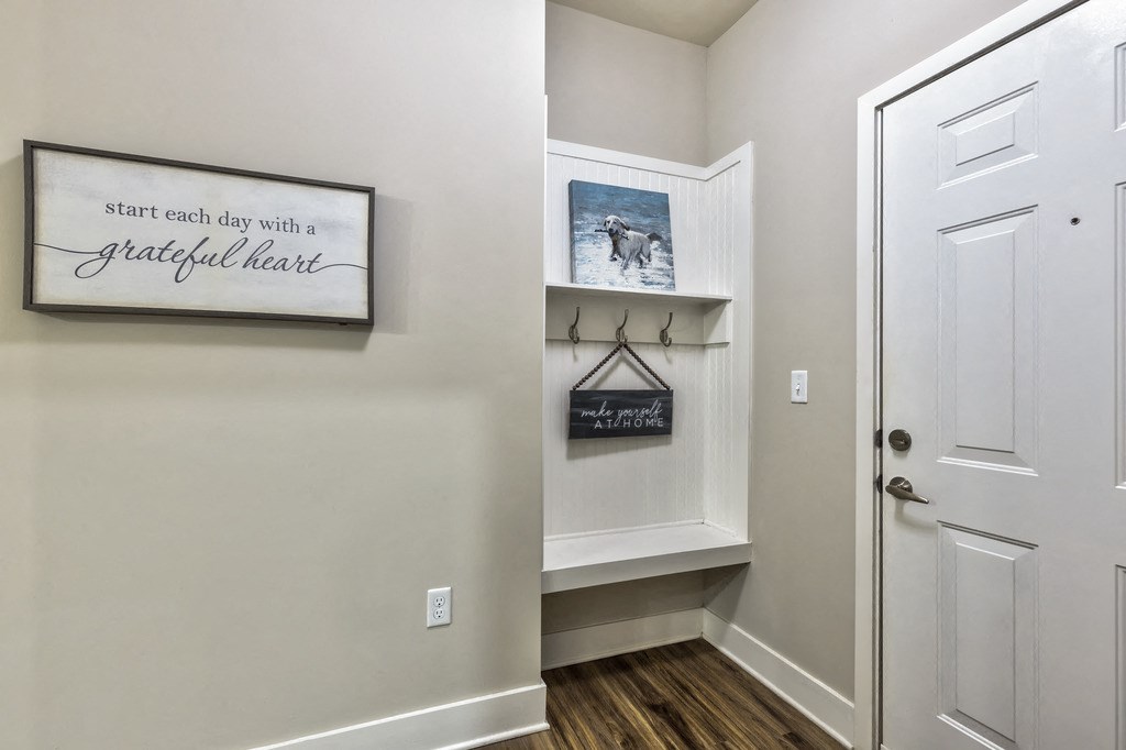 a hallway with white walls and a closet with a white door and a wall hanging