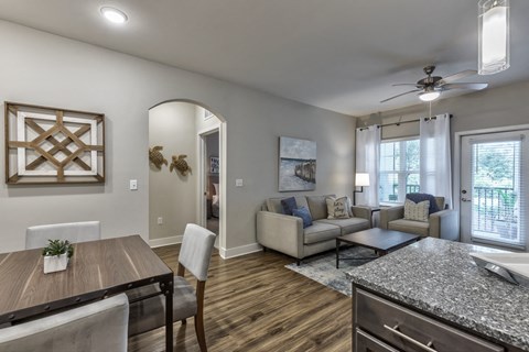 a living room with couches and a table and a kitchen
