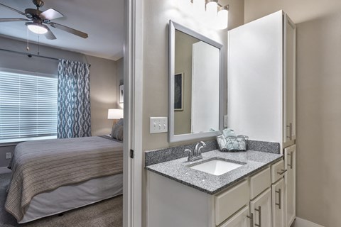 a bathroom with a sink and a mirror and a bedroom with a bed