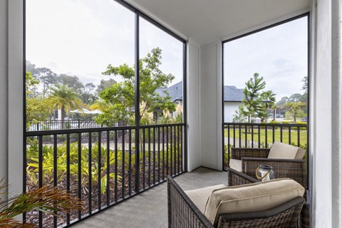a balcony with a couch and chairs and large windows