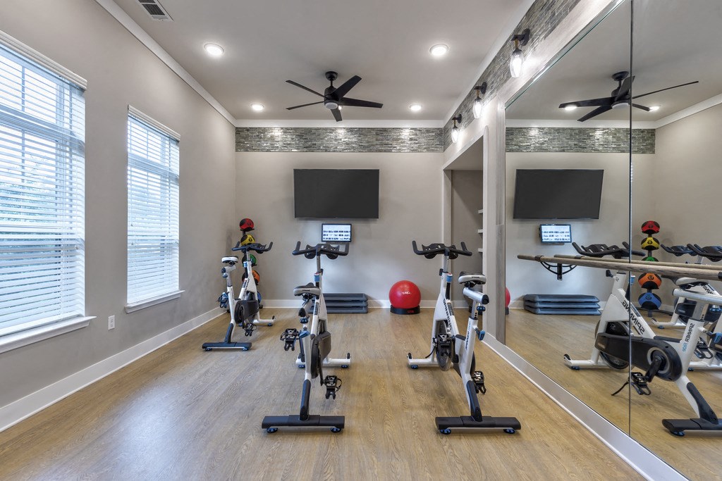a gym with treadmills and weights and a tv