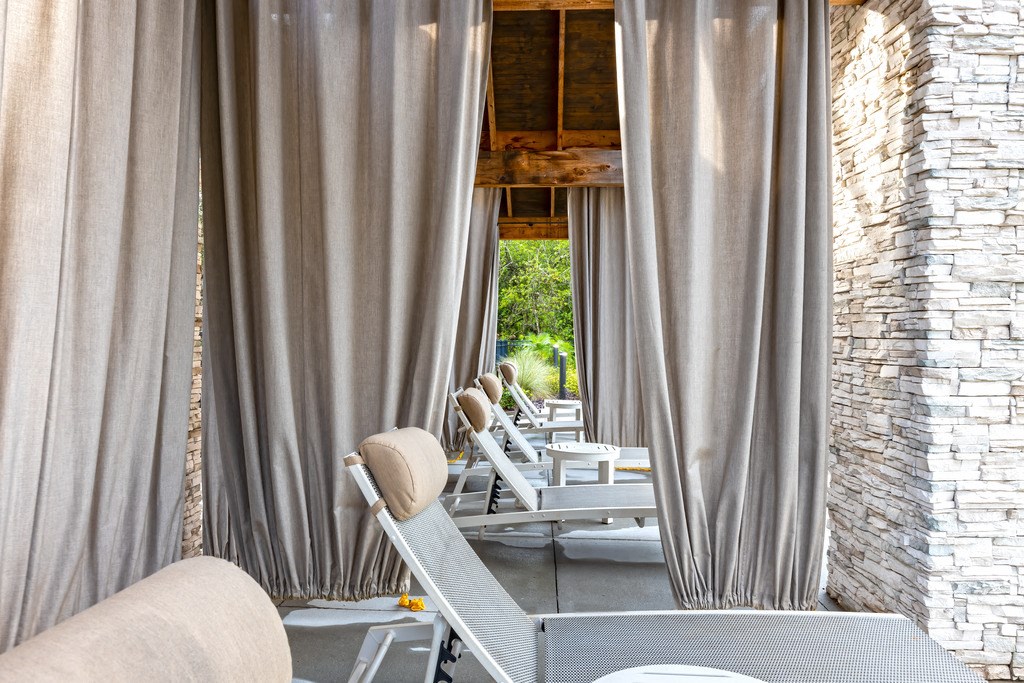 a patio with chairs and curtains and a row of chairs in front of a window