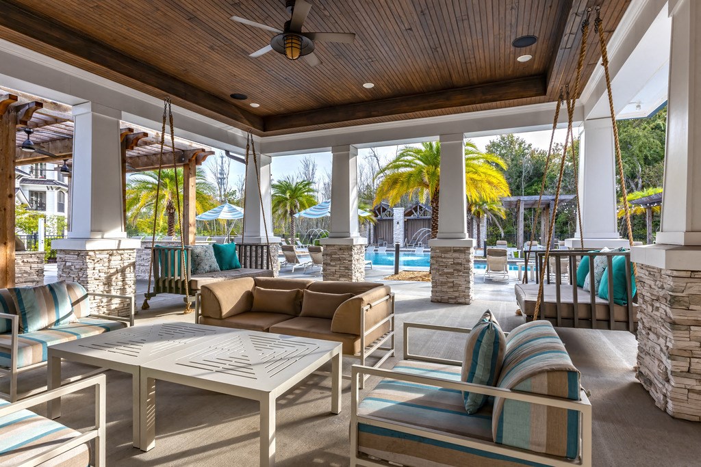 a covered patio with couches and chairs and a swimming pool