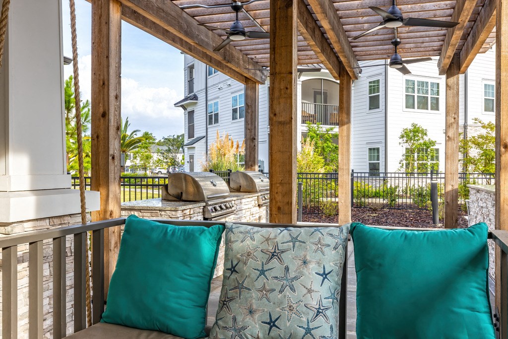 a covered patio with a grill and blue pillows on it