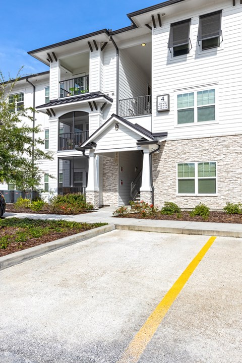 a white apartment building with a driveway and a garage door