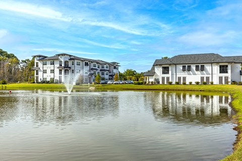 a fountain in the pond with apartments in the background