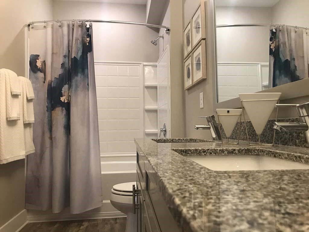 A bathroom with a marble counter top and a shower curtain. at Foxwood Apartments, Raleigh-Durham, NC