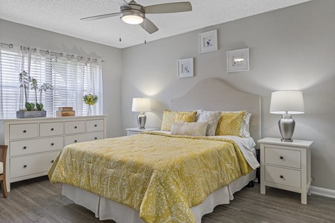 A bedroom with a bed, nightstands, and a ceiling fan.