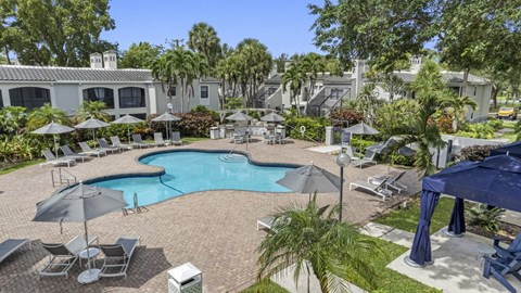 A pool surrounded by chairs and landscaping.