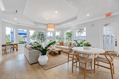 A living room with a white couch, a white coffee table, and a white vase with a plant in it.