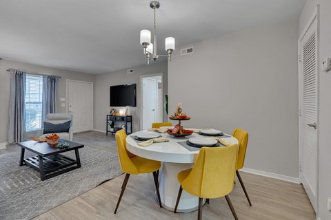 A dining room with a white table and yellow chairs.
