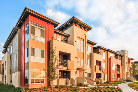 A modern apartment building with red and beige facades.