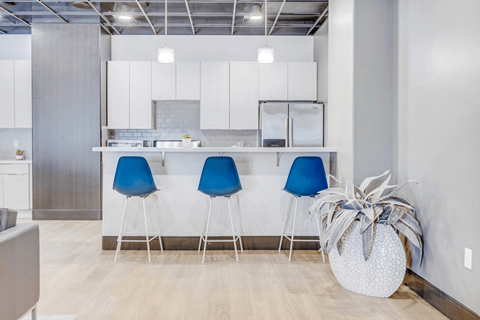 A kitchen with a white counter and blue chairs.