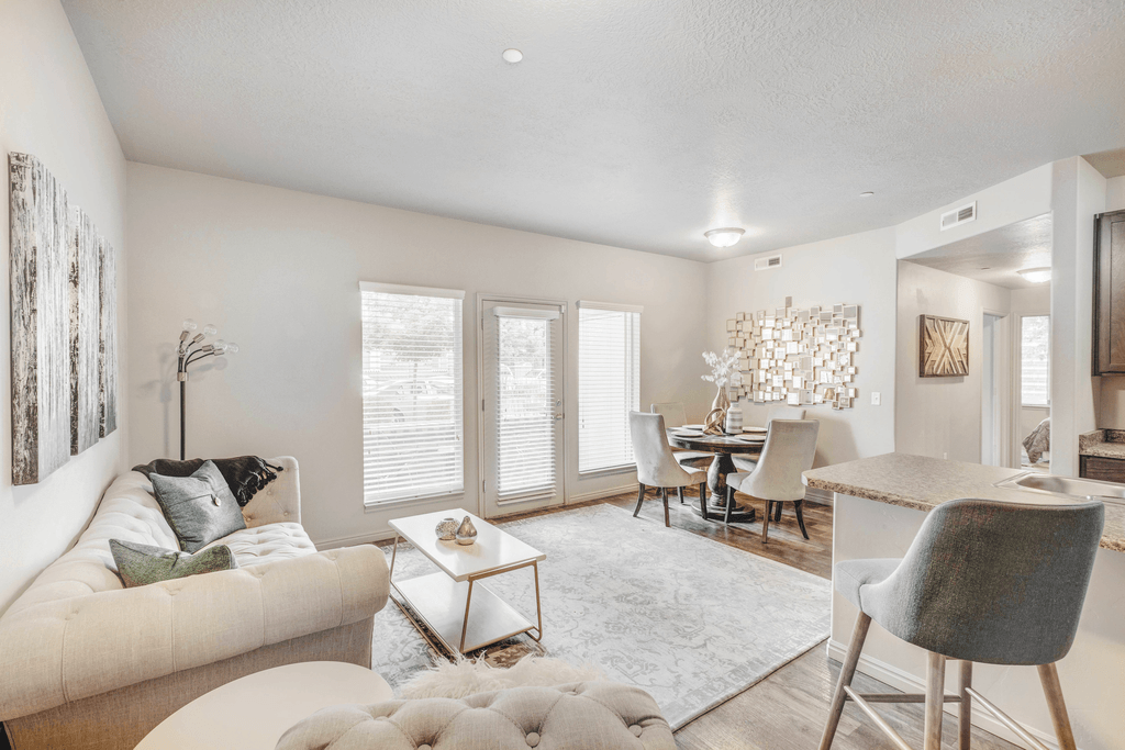 a staged living room and dining room with hardwood-style flooring and windows