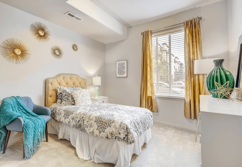 A bedroom with a bed, chair, and decorative wall items.