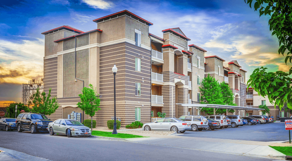 A large apartment complex with cars parked in front.