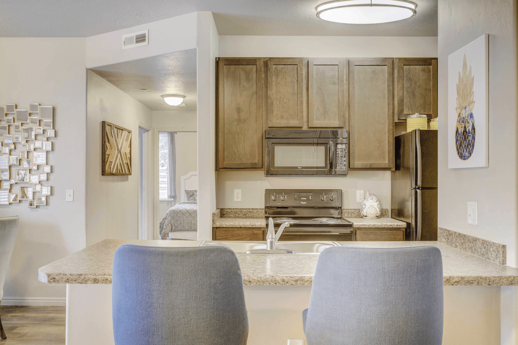 A kitchen with a countertop and two chairs in front of it.