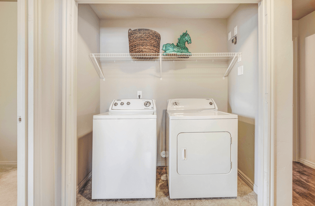 Laundry area with white washer and dryer with shelf