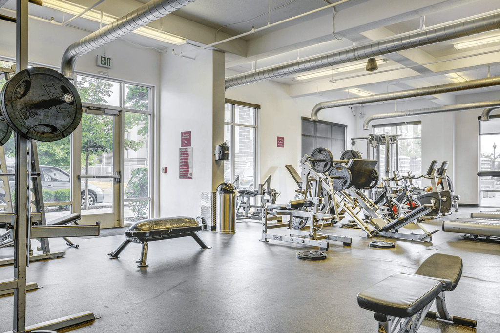 A gym with a variety of equipment including weights and benches.