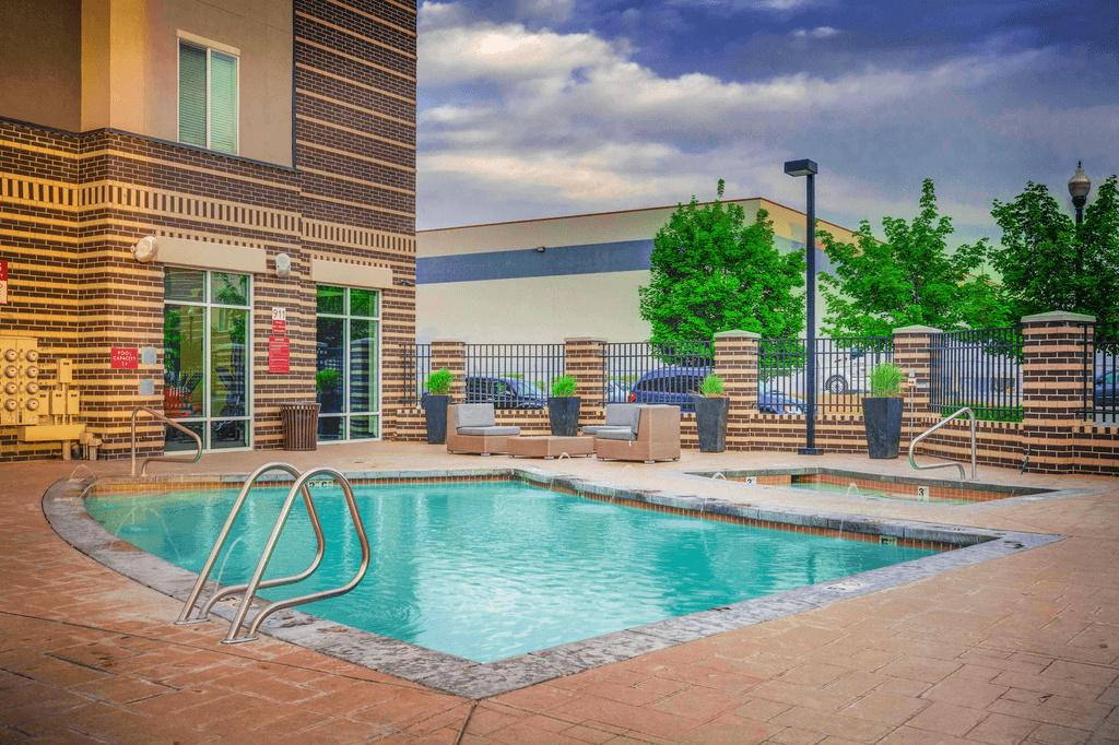 Swimming pool and heated spa with tanning deck, outdoor lounge seating with building exterior