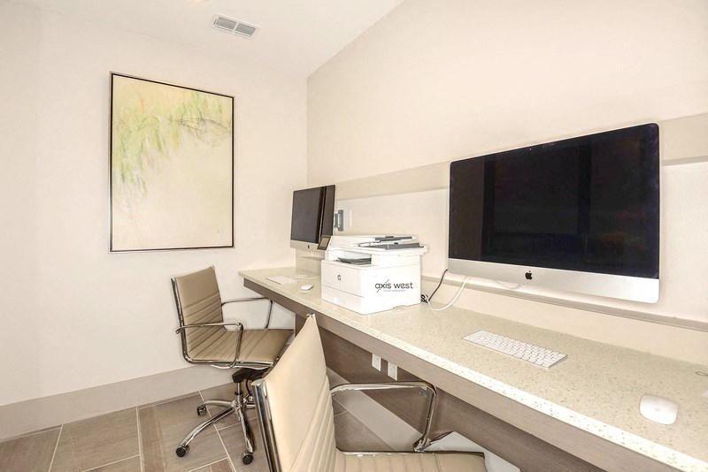 a computer desk with a monitor and two chairs in a room